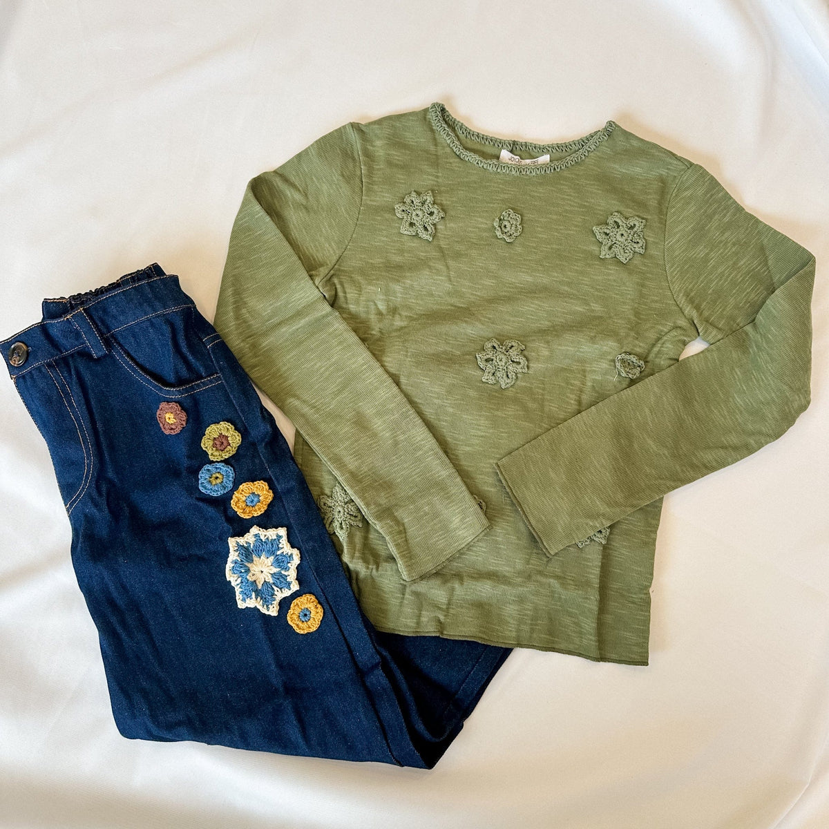 Green embroidered long-sleeve top and blue jeans with floral embroidery